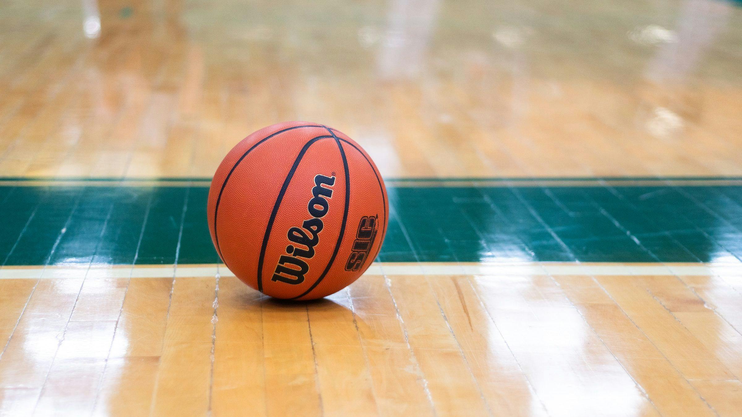 A basketball on the floor of a gym.